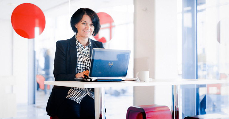 Kvinna sitter vid skrivbord med en laptop